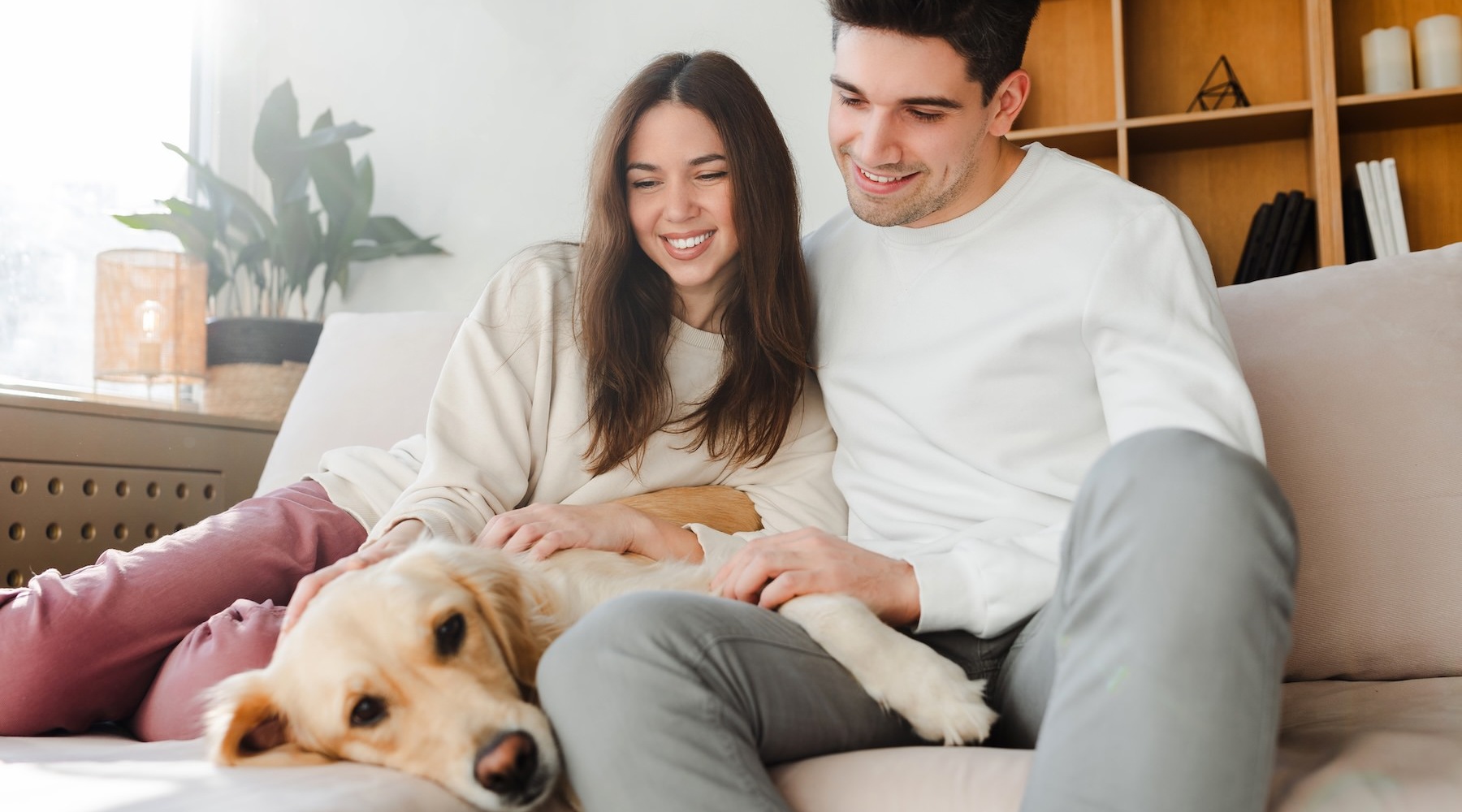 a man and woman sitting on a couch with a dog